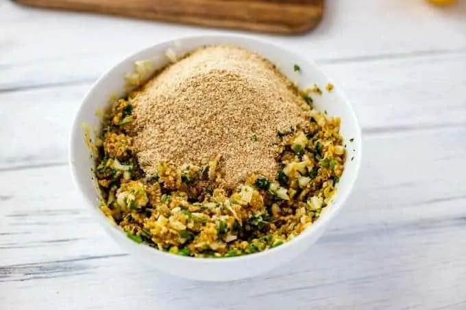 Photo of breadcrumbs being added to other ingredients for quinoa cakes.
