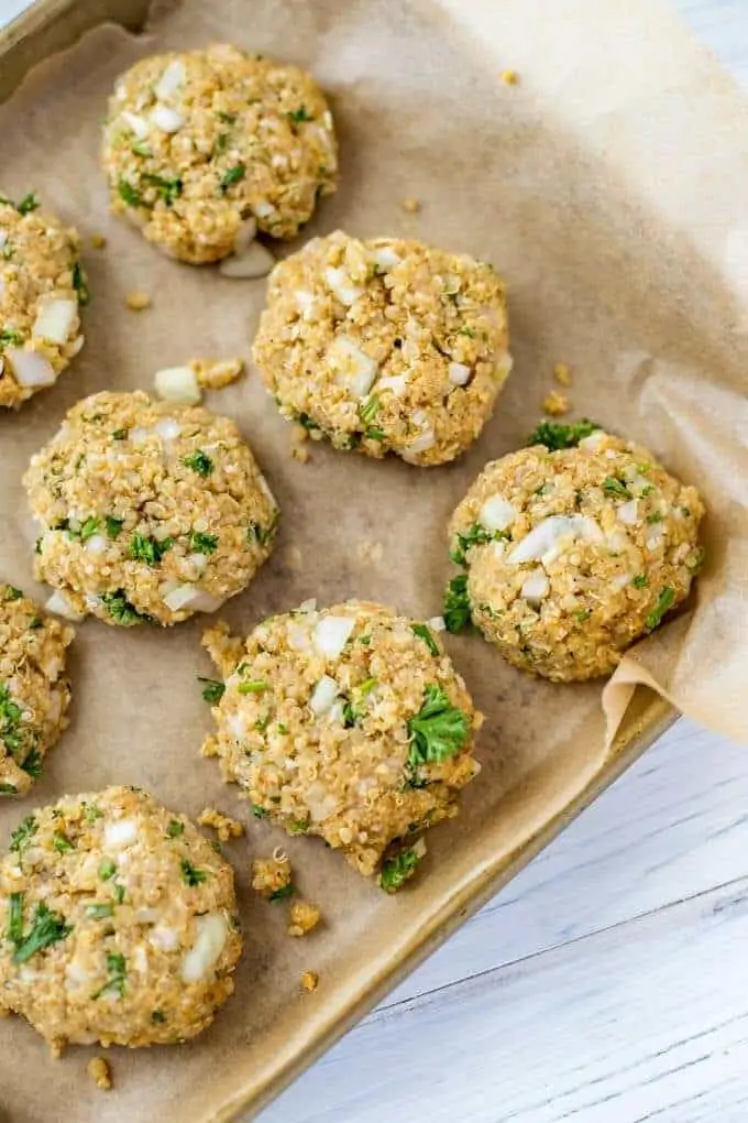 Photo of uncooked quinoa patties formed on a parchment lined baking sheet.