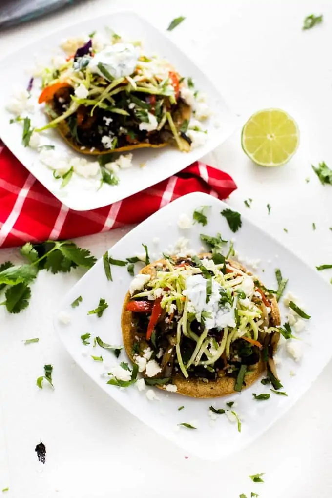 Two plates of Black Bean and Quinoa Tostadas with a lime garnish.