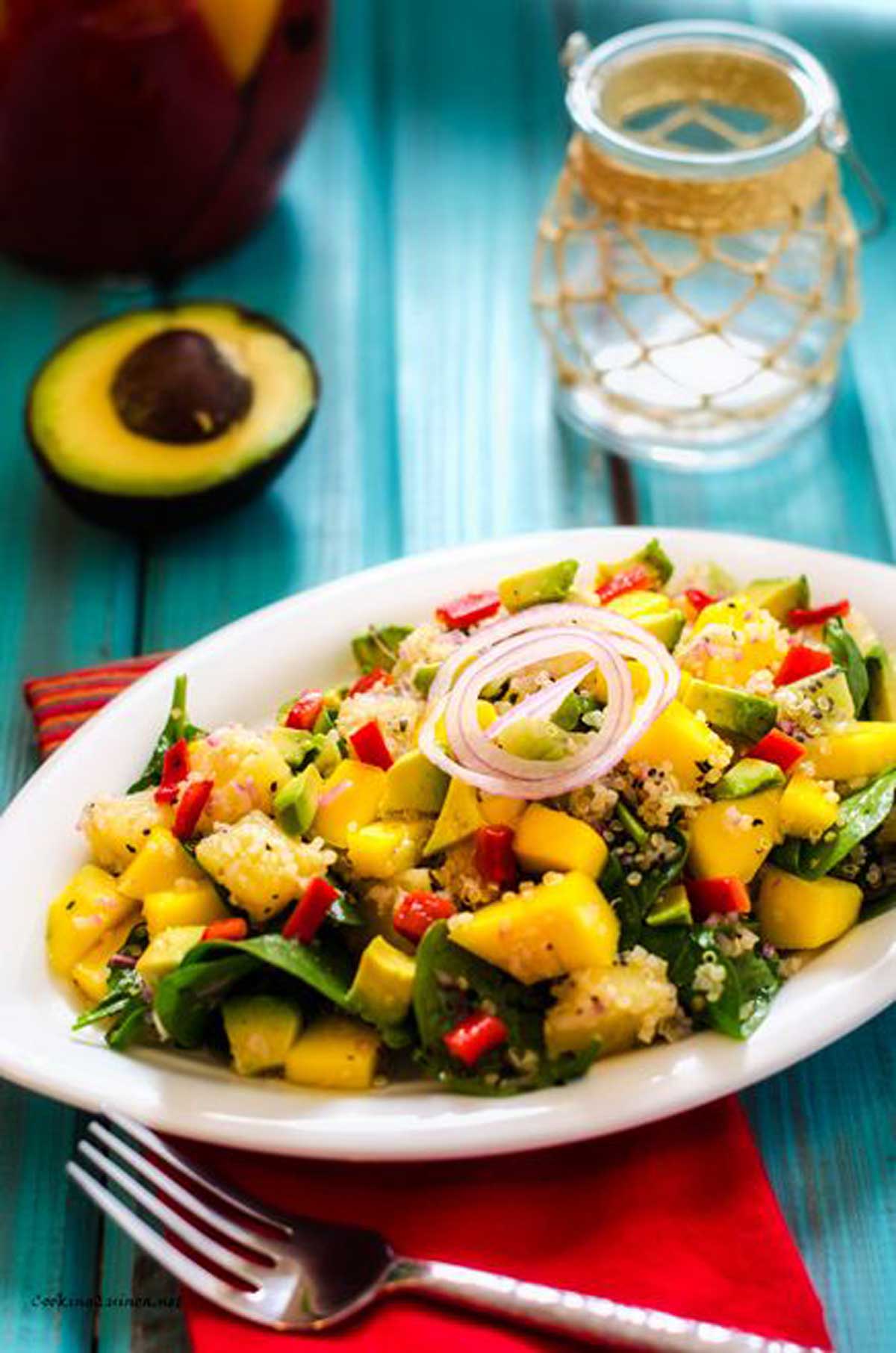 Photo of a platter of Avocado Mango Quinoa Salad garnished with a quick pickled onion.