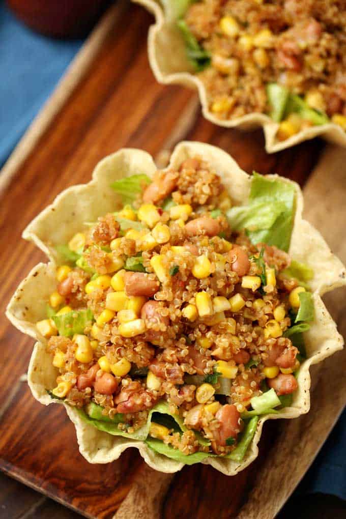 Photo of a quinoa bean and corn mixture over lettuce in a tortilla bowl.