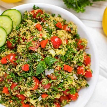 Overhead photo of a shallow serving dish with Quinoa Tabbouleh garnished with mint and cucumber.