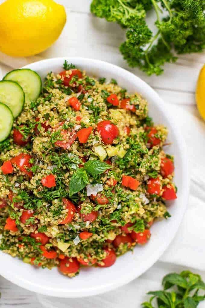 Close-up overhead photo of a shallow serving dish with Quinoa Tabbouleh garnished with mint and cucumber.