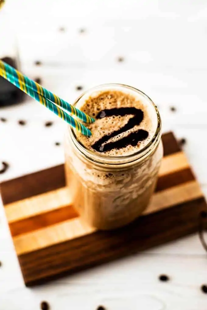 Photo of a Quinoa Smoothie with coffee in a mason jar with a blue and yellow striped jar.