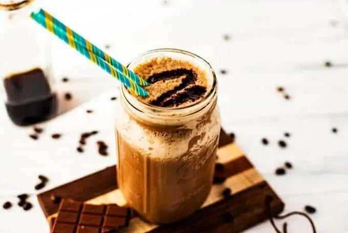 Horizontal photo of a vegan quinoa smoothie in a glass jar surrounded by coffee beans.