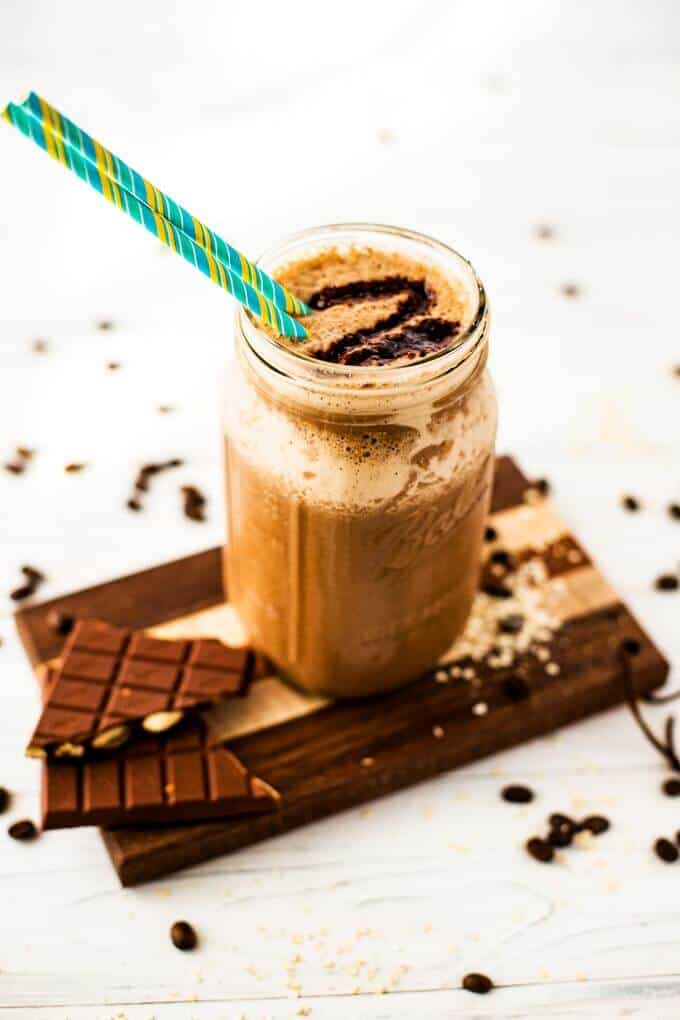 Vertical image of coffee quinoa smoothie in a mason jar sitting on a cutting board.
