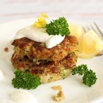 Close up square image of zucchini quinoa fritters on a white plate.