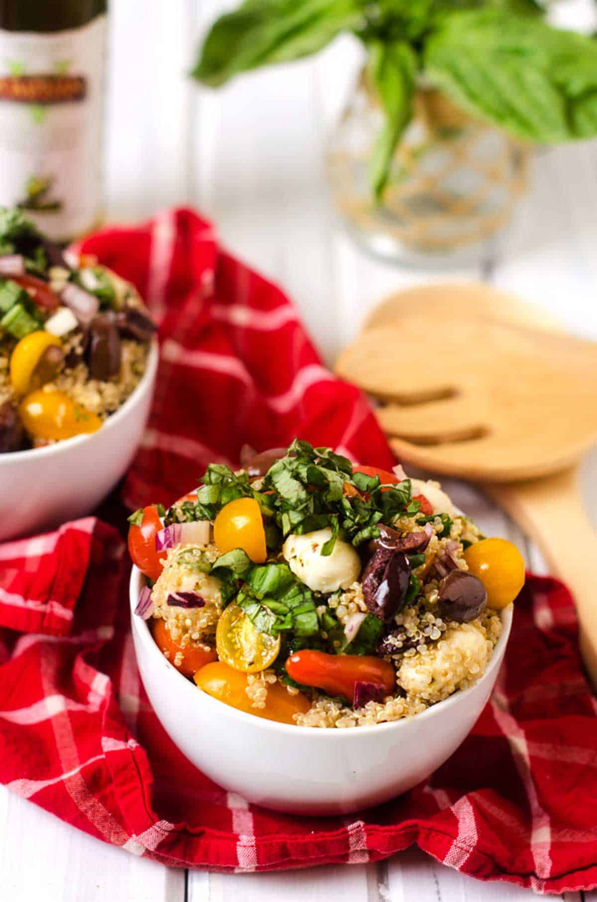 Photo of a bowl of caprese quinoa salad on a red and white cloth napkin.
