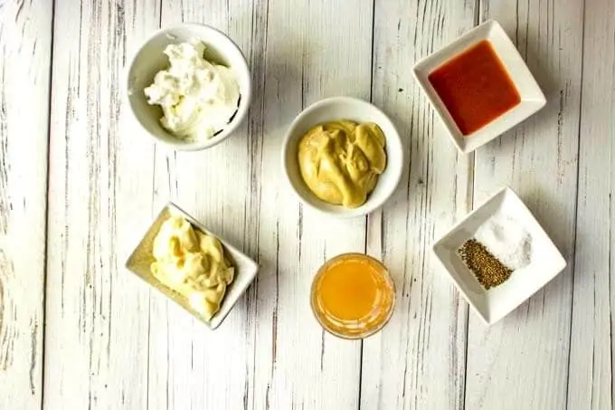 Photo of mayo, Greek yogurt, apple cider vinegar, Dijon mustard, sweetener, hot sauce, sea salt, and celery seeds in small prep bowls.