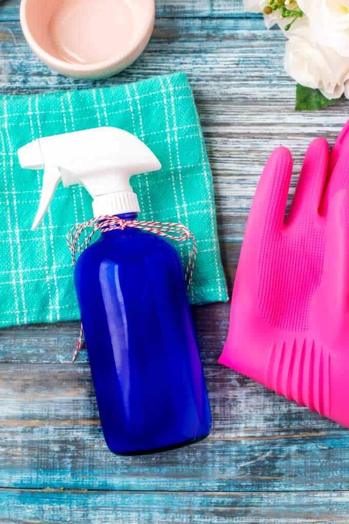 Final Photo of DIY All Purpose Cleaner in a blue glass bottle sitting next to pink cleaning gloves.
