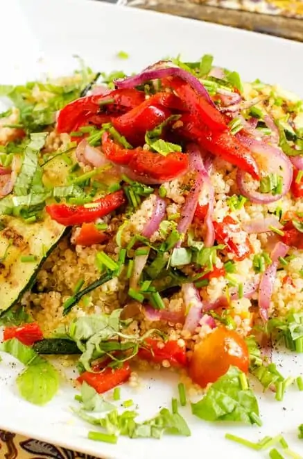 Close up photo of Vegetable Quinoa Salad on a white plate garnished with herbs.