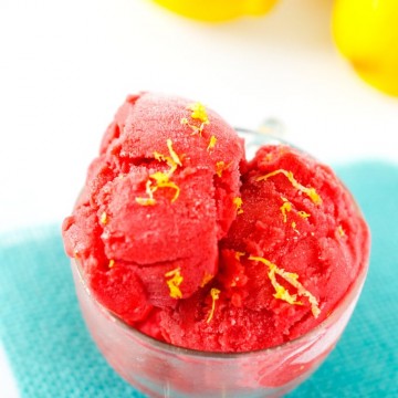 Photo of a glass of strawberry sorbet on a bright blue napkin.