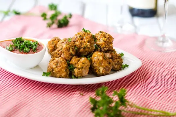 Side photo of Beef and Quinoa Meatballs on a white platter sitting on a red and white napkin.