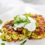 Photo of prepared Zucchini Fritters Recipe with Feta on a white plate.