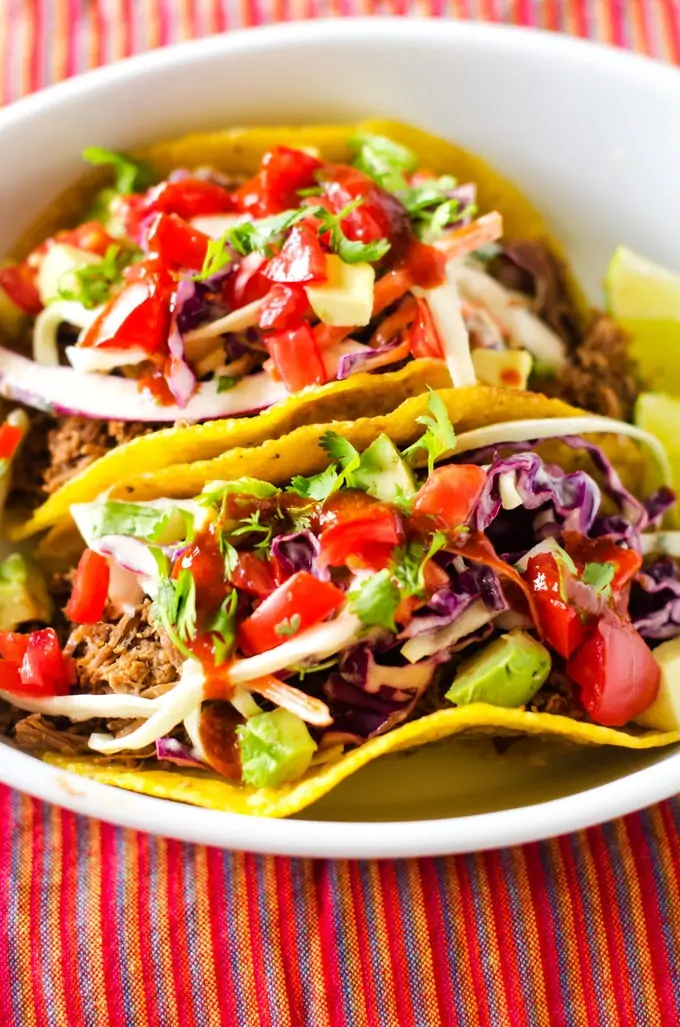 Photo of two Shredded Beef Tacos with Chipotle Lime Slaw in a small white dish.