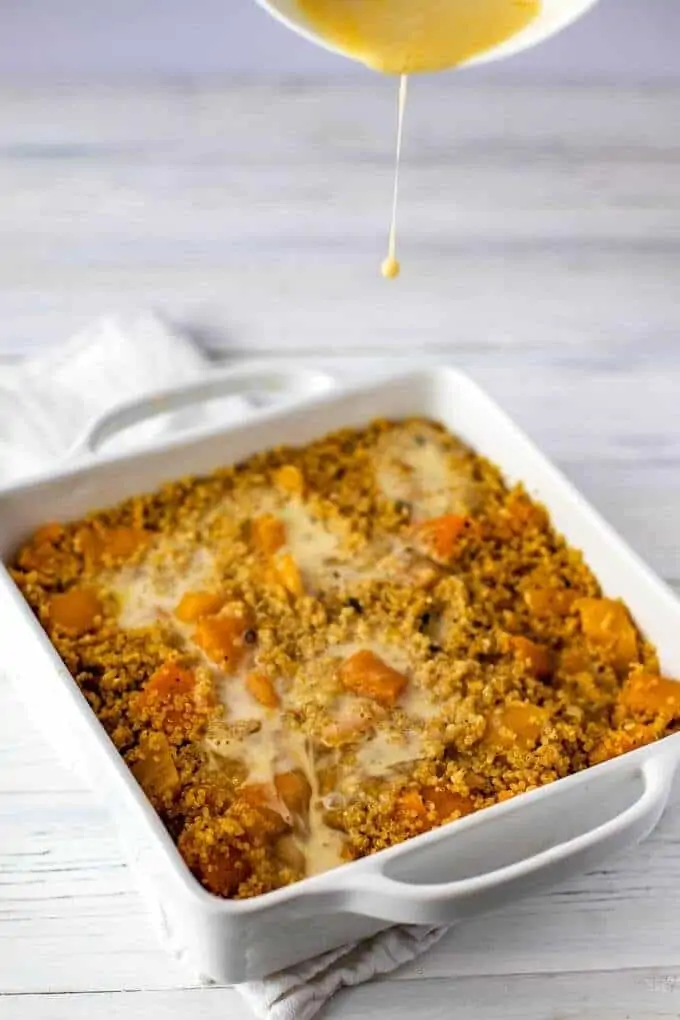 Butternut Squash Casserole in a baking dish with the egg mixture being added to the pan.