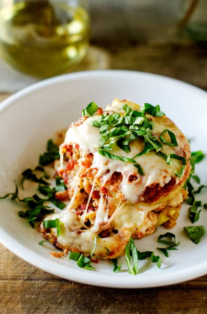 ¾ overhead photo of Slow Cooker Eggplant Parmesan with stringy cheese garnished with fresh basil and a glass of white wine behind it.