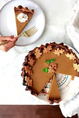 Photo of a vegan pumpkin pie slice at the top with the remainder of the whole pie below.