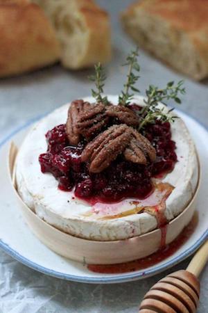 Close up photo of cranberry baked brie on a white plate.