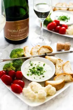 Photo of goat cheese gruyere fondue surrounded by bread cubes and vegetables. 