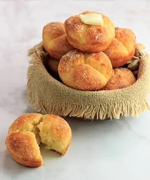 Photo of keto pull apart clover rolls in a bowl with one sitting beside the bowl.
