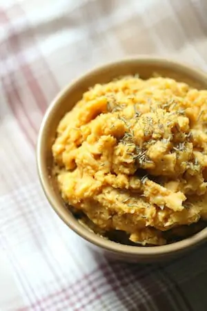 Photo of Savory Pumpkin Hummus in a tan bowl on a plaid background.