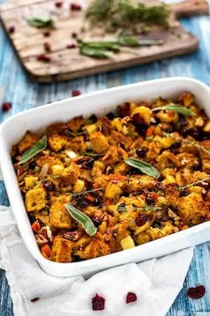 Photo of gluten free stuffing in a white casserole dish garnished with sage.