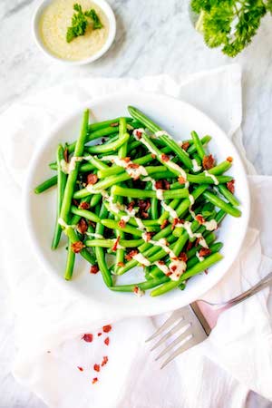 Overhead photo of Green Beans with Bacon on a white plate against a white background.