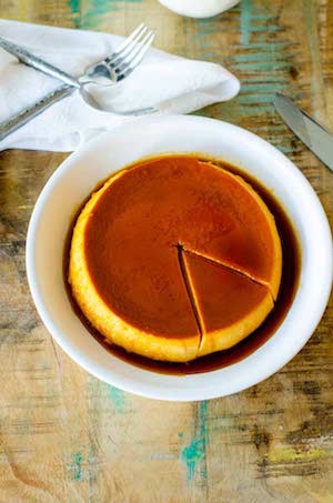 Photo of Pumpkin Flan on a white plate against a rustic wood background.