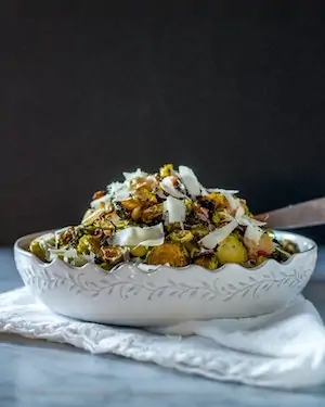 Photo of shredded Roasted Brussels Sprouts in a white bowl against a dark background.