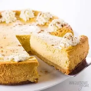 Photo of low carb Pumpkin Cheesecake in a white pie plate against a white background.