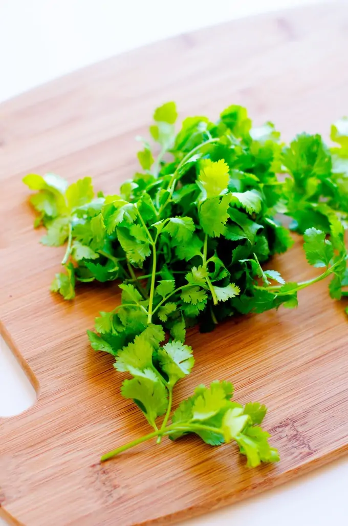 Photo of cilantro on a wooden cutting board.