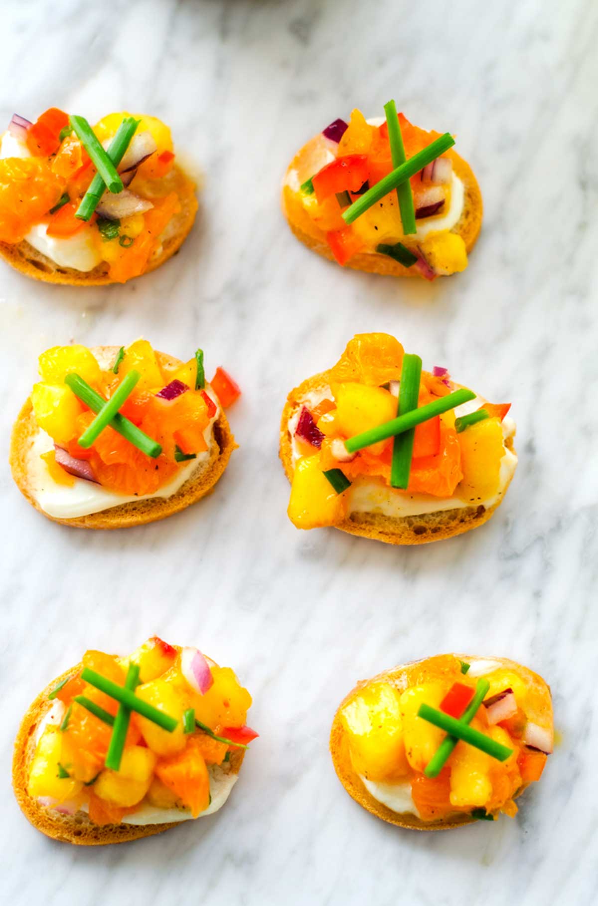 Overhead photo of goat cheese crostini on a marble background.
