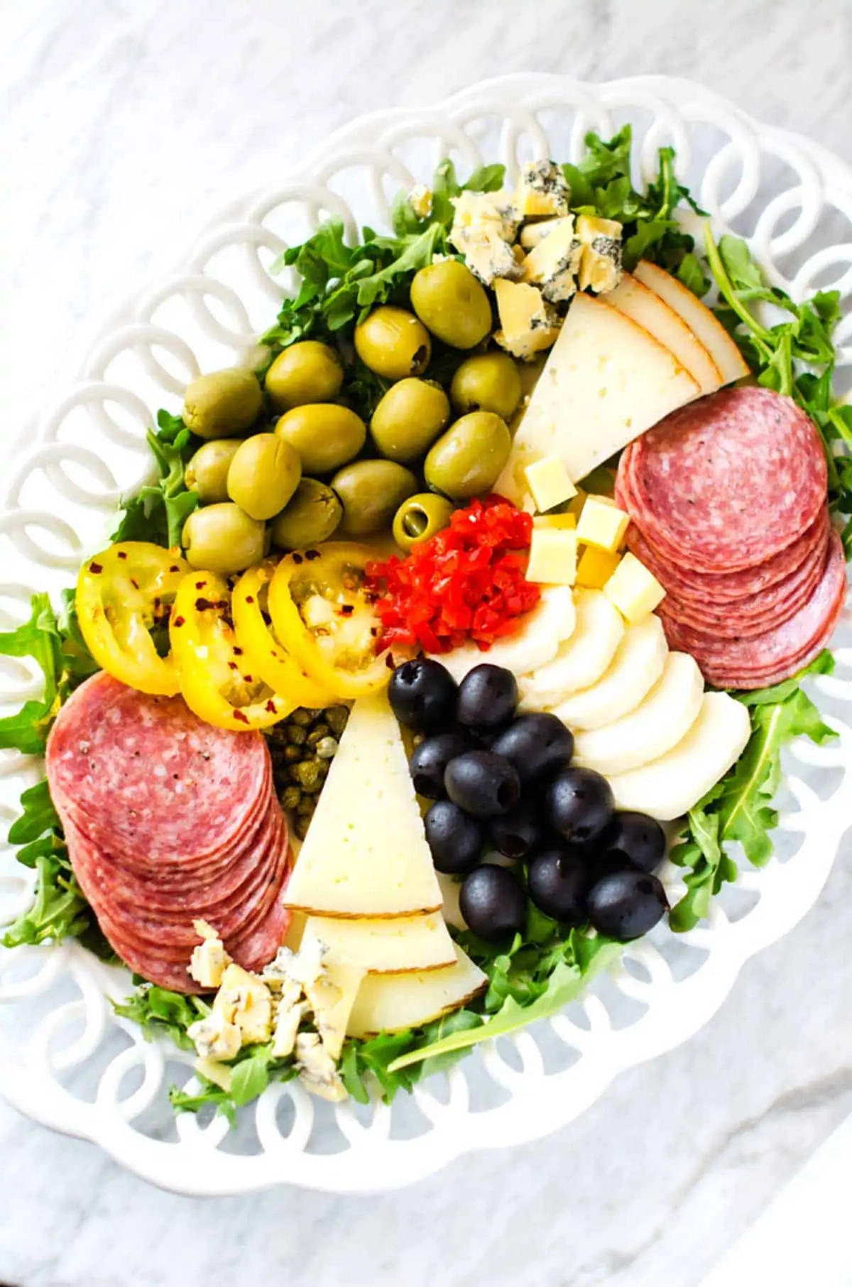 Overhead photo of an antipasto platter against a white marble background.