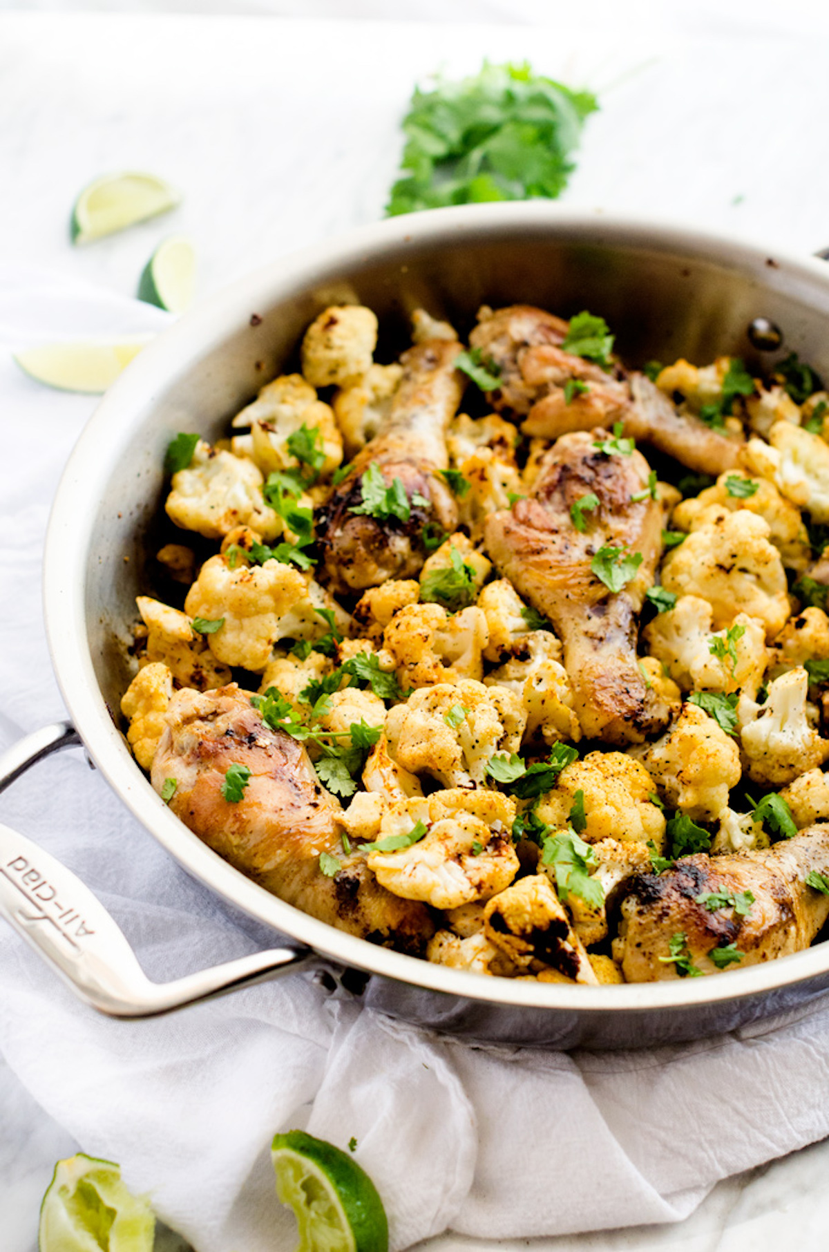 Chicken and cauliflower in a skillet garnished with parsely.