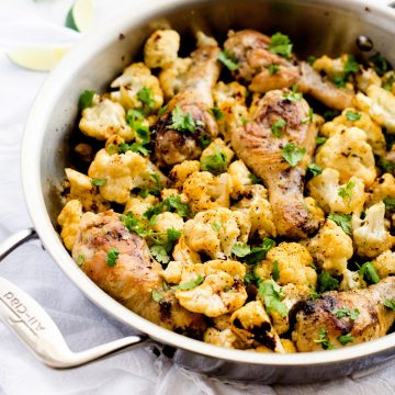 Square photo of chicken and cauliflower in a skillet garnished with parsely.