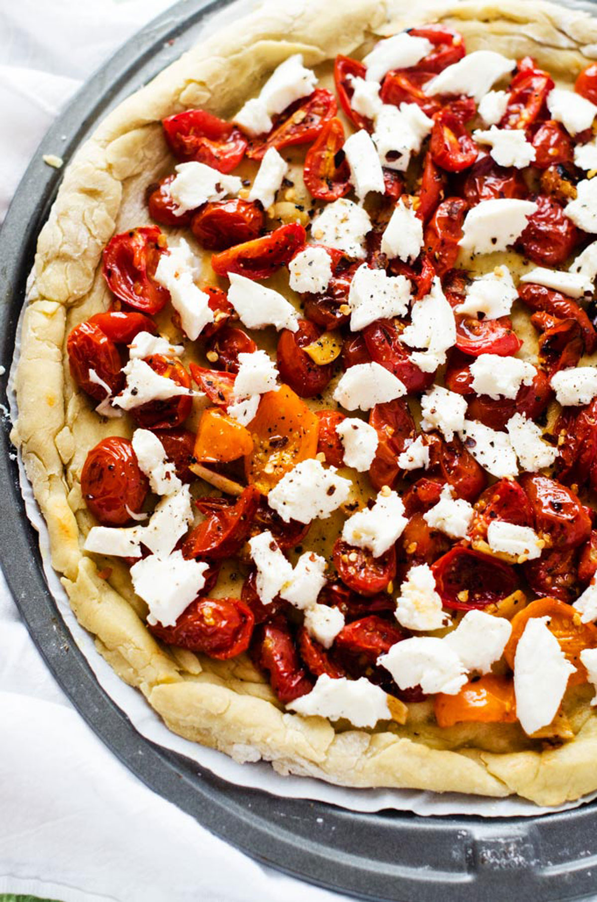 A caprese pizza that has been topped and is ready for the oven.