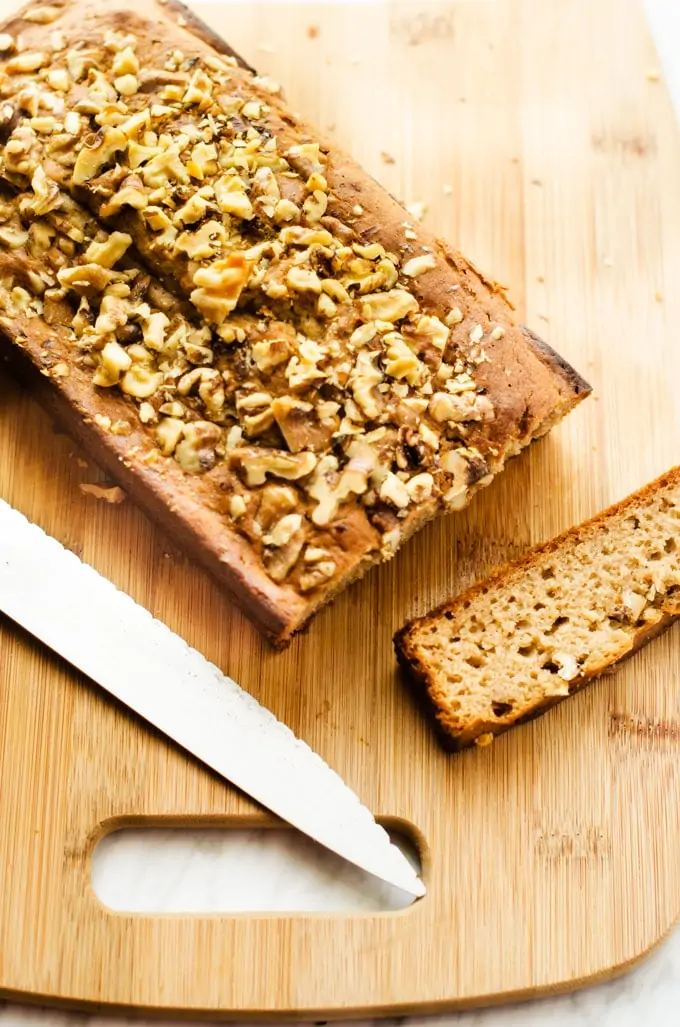 Photo of a loaf of Gluten Free Apple Bread on a cutting board with one slice cut out and a knife sitting next to it.