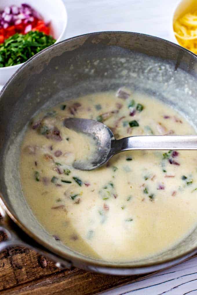 Photo of milk added to the cooked vegetables for a homemade queso dip recipe.