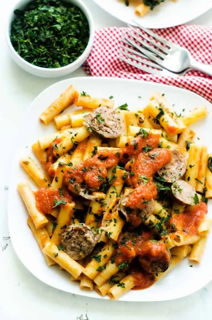Photo of Sausage and Spinach Pasta on a white plate garnished with parsley.
