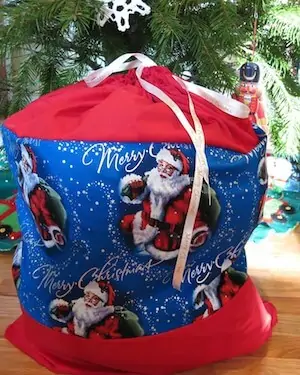 Photo of a DIY Santa Sack for toy donations sitting in front of a Christmas tree.