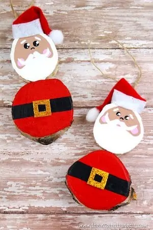Photo of two wooden Santa crafts for kids on a white rustic background.