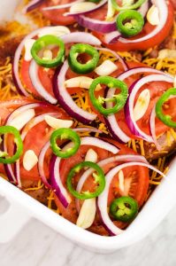 Photo of southwest baked chicken topped with cheese, tomato, red onion, garlic, and jalapeno.
