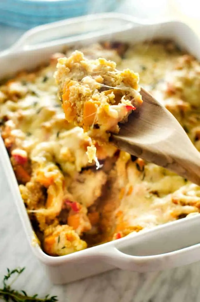 Photo of a spoonful of quinoa casserole piping hot from the oven over a casserole dish filled with sweet potato quinoa casserole.