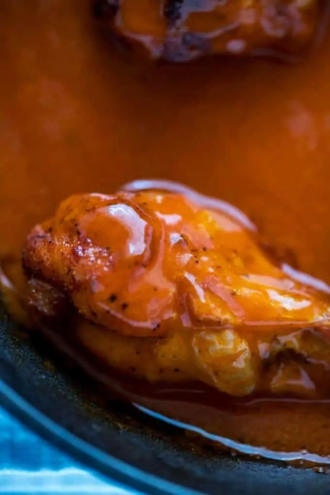 Close up photo of a baked chicken wing in buffalo sauce.