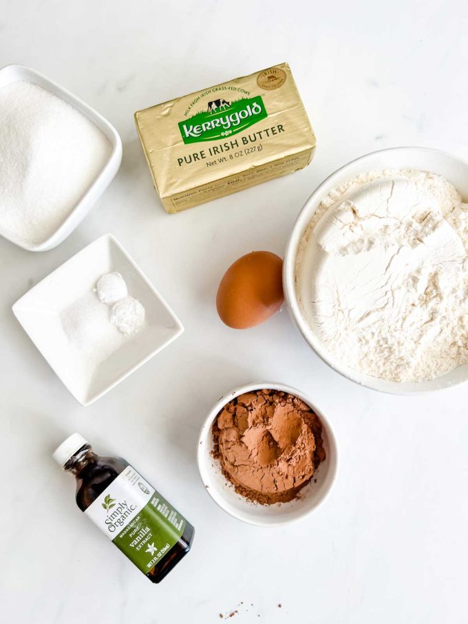 Photo of butter, flour, cocoa powder, egg, sugar, vanilla, salt, and baking powder in prep bowls.