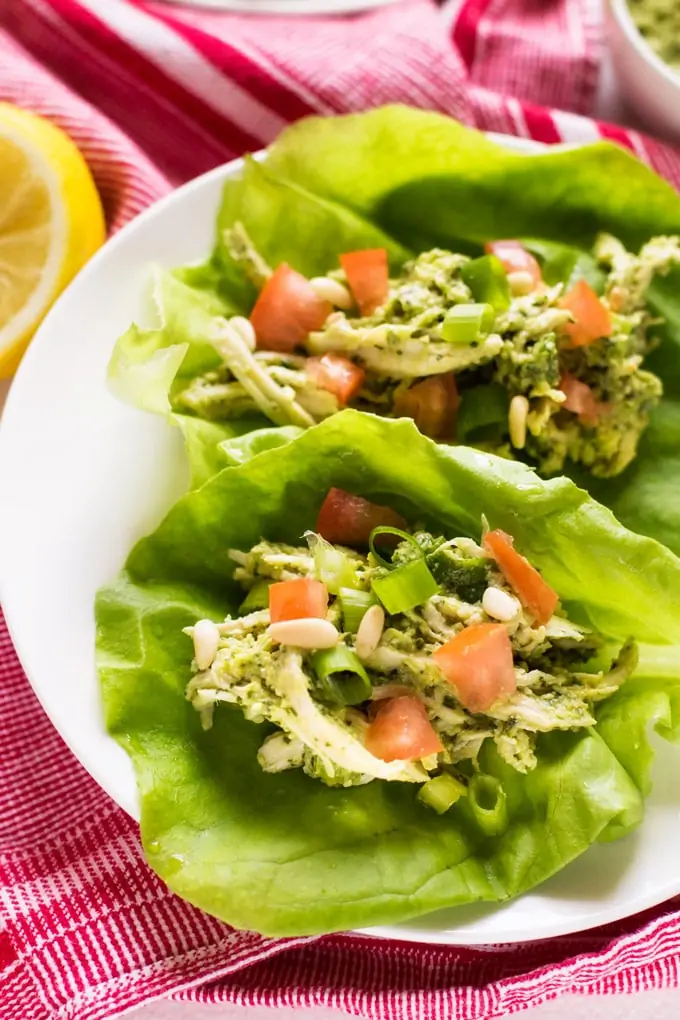 Side photo of pesto chicken salad in a lettuce wrap on a white plate.