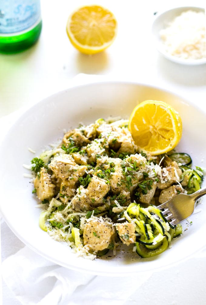 ¾ overhead shot of Zucchini noodle alfredo with chicken in a white bowl on a white background.