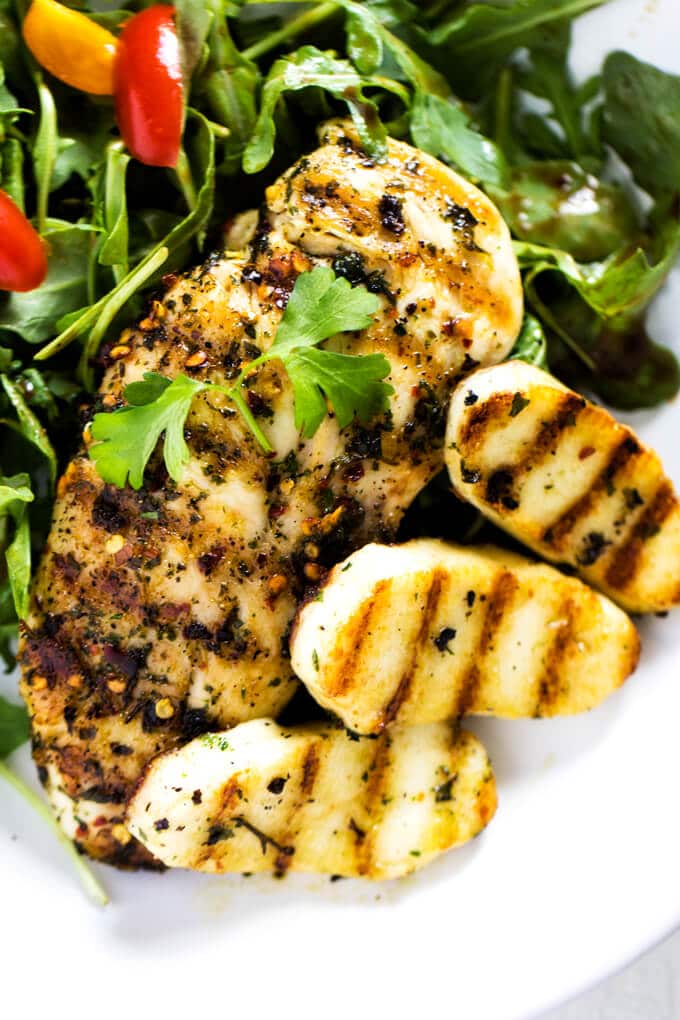 Close up photo of chicken and halloumi salad on a white plate.