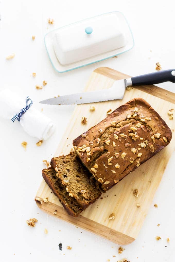 Overhead photo of Healthy Gluten Free Banana Bread sitting on a cutting board on a white background.